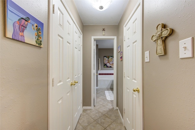 hall with a textured ceiling and light tile patterned flooring