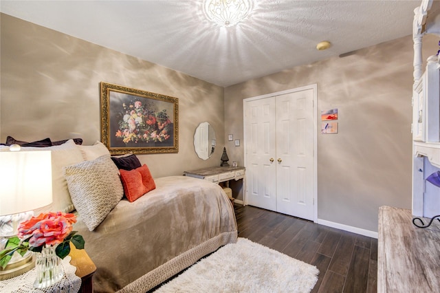 bedroom with a textured ceiling, dark wood-type flooring, and a closet