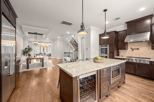 kitchen featuring a center island, hanging light fixtures, beverage cooler, tasteful backsplash, and built in appliances