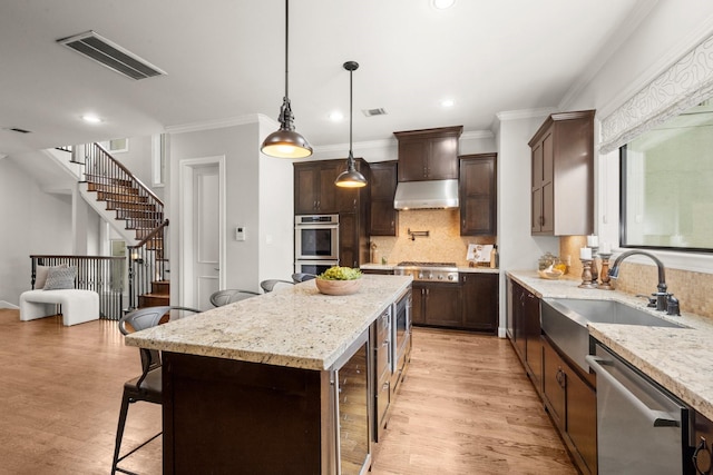 kitchen featuring light stone countertops, appliances with stainless steel finishes, a kitchen breakfast bar, sink, and a kitchen island