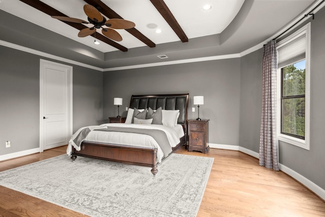 bedroom with a tray ceiling, ceiling fan, light hardwood / wood-style floors, and ornamental molding