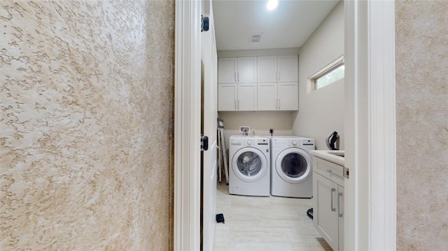 laundry area featuring washer and dryer and cabinets