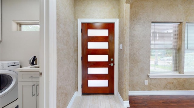 clothes washing area featuring plenty of natural light, light hardwood / wood-style flooring, cabinets, and washer / dryer