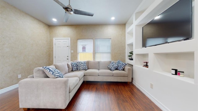 living room featuring built in shelves, ceiling fan, and dark hardwood / wood-style floors