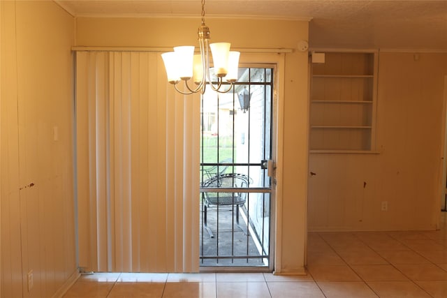 doorway to outside featuring tile patterned floors, built in shelves, a chandelier, and ornamental molding