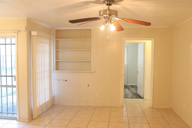 tiled spare room with ceiling fan, built in features, ornamental molding, and wooden walls