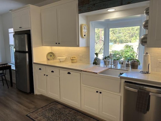 kitchen with white cabinetry, sink, dark wood-type flooring, backsplash, and appliances with stainless steel finishes