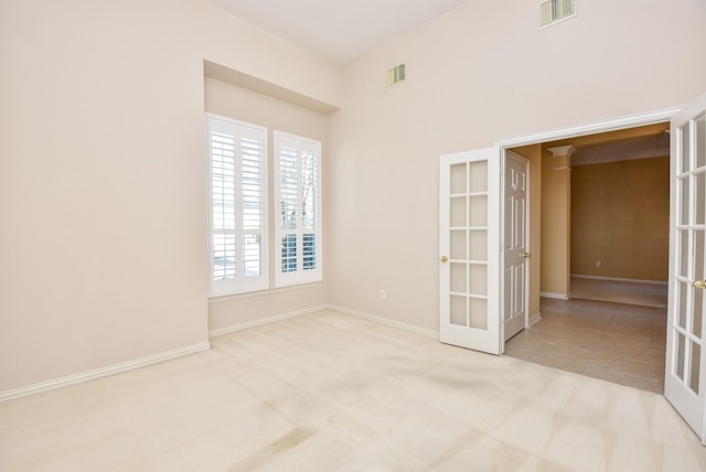 empty room featuring french doors and light colored carpet