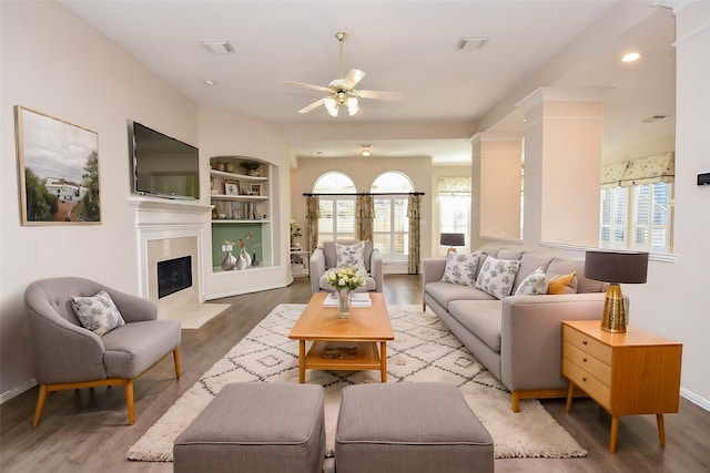 living room featuring built in shelves, ceiling fan, and hardwood / wood-style flooring