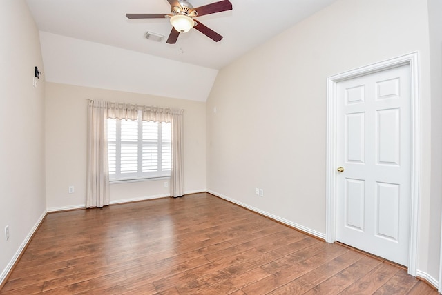 empty room with dark hardwood / wood-style flooring, vaulted ceiling, and ceiling fan