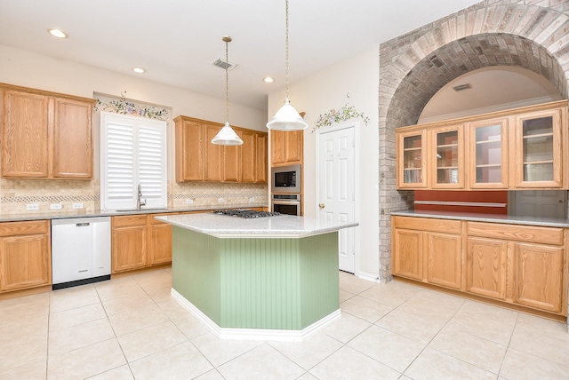 kitchen featuring appliances with stainless steel finishes, tasteful backsplash, sink, decorative light fixtures, and a kitchen island