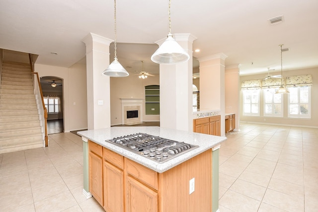 kitchen featuring stainless steel gas stovetop, a center island, ceiling fan, decorative light fixtures, and light tile patterned flooring