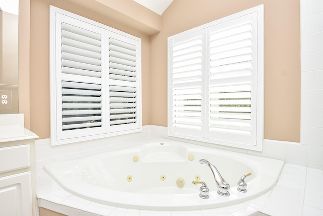 bathroom with vanity, a relaxing tiled tub, and vaulted ceiling