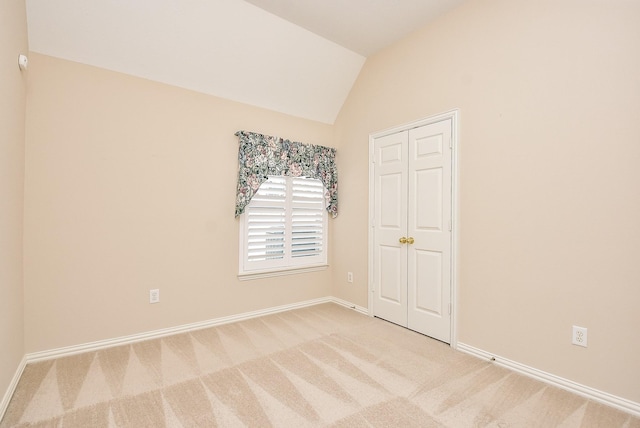 unfurnished bedroom featuring light colored carpet and lofted ceiling