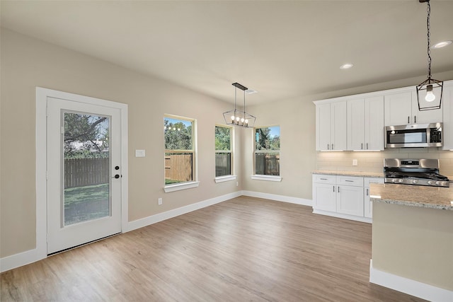 kitchen featuring white cabinetry, light stone countertops, stainless steel appliances, tasteful backsplash, and decorative light fixtures