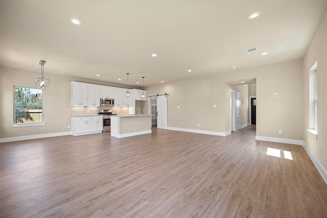 unfurnished living room featuring a barn door and light hardwood / wood-style flooring