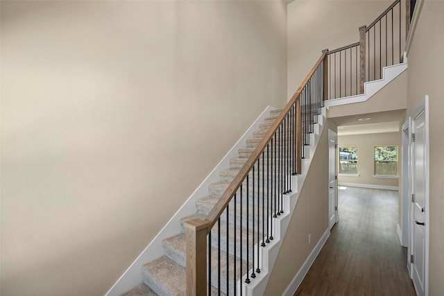 stairway featuring hardwood / wood-style floors and a towering ceiling