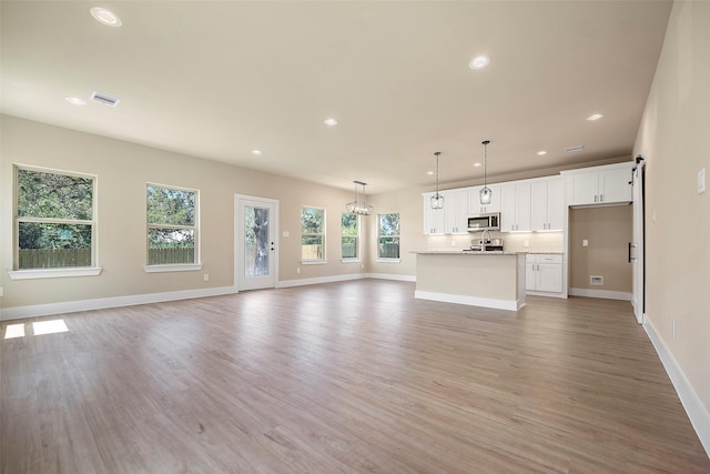 unfurnished living room with light hardwood / wood-style flooring and a healthy amount of sunlight