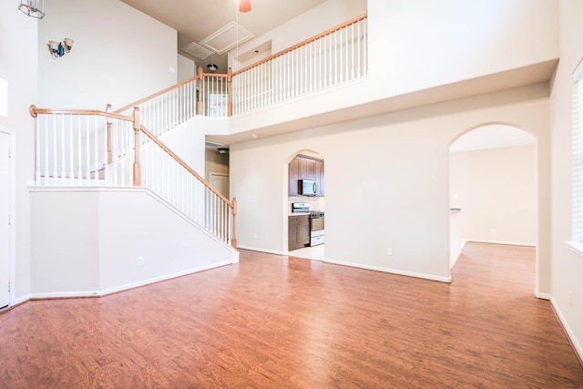 unfurnished living room featuring a towering ceiling and hardwood / wood-style flooring