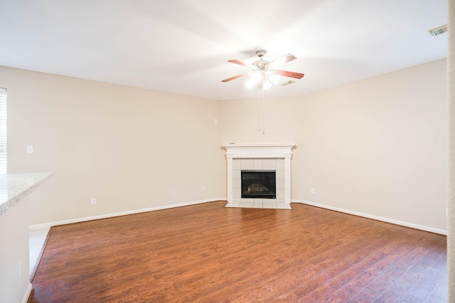 unfurnished living room with hardwood / wood-style floors, ceiling fan, and a tile fireplace