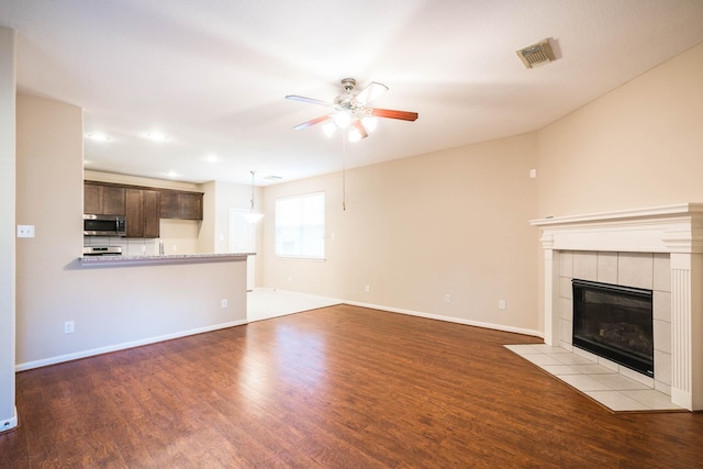 unfurnished living room featuring light hardwood / wood-style floors, ceiling fan, and a tiled fireplace