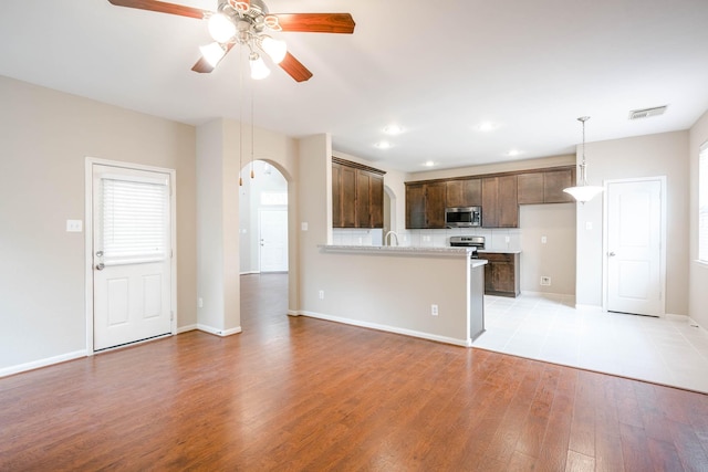 kitchen with kitchen peninsula, appliances with stainless steel finishes, ceiling fan, a healthy amount of sunlight, and light hardwood / wood-style flooring