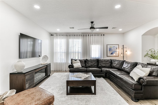 living room featuring a textured ceiling, light hardwood / wood-style flooring, and ceiling fan