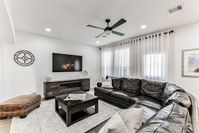 living room featuring hardwood / wood-style floors, a textured ceiling, and ceiling fan