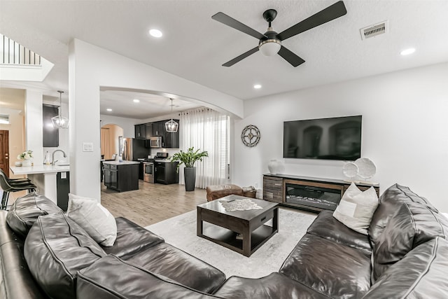 living room featuring ceiling fan with notable chandelier and light hardwood / wood-style floors