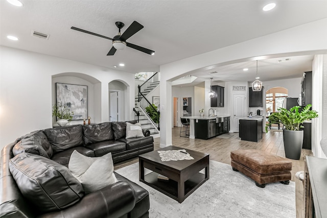 living room with ceiling fan, sink, and light hardwood / wood-style floors