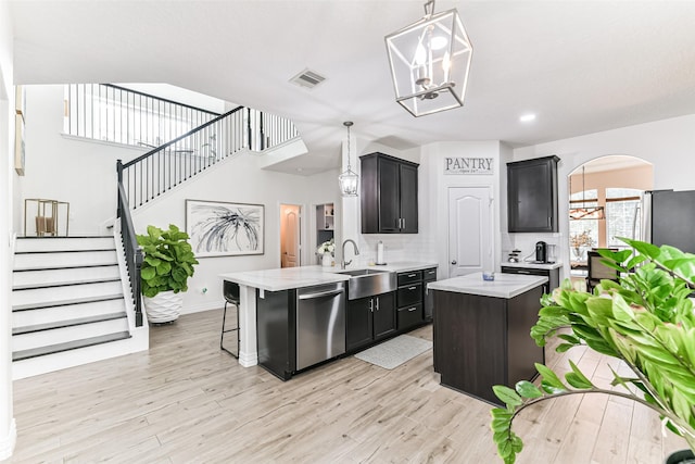 kitchen with sink, light hardwood / wood-style flooring, stainless steel dishwasher, tasteful backsplash, and a kitchen island