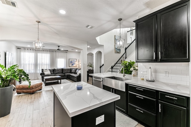 kitchen with dishwasher, sink, a center island, light hardwood / wood-style floors, and decorative light fixtures