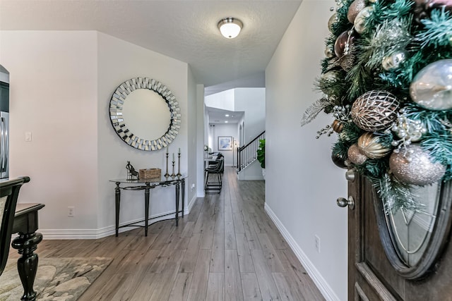 corridor featuring light hardwood / wood-style floors and a textured ceiling