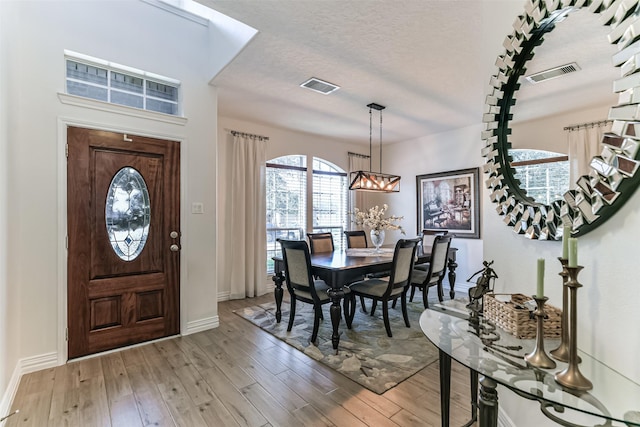 entryway with hardwood / wood-style floors, a textured ceiling, and a notable chandelier