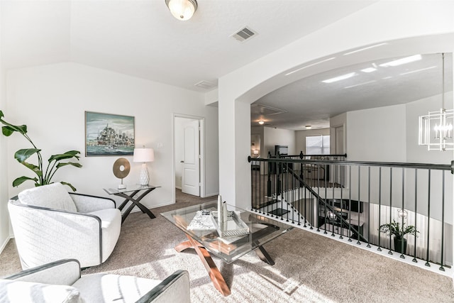 carpeted living room featuring a notable chandelier and vaulted ceiling