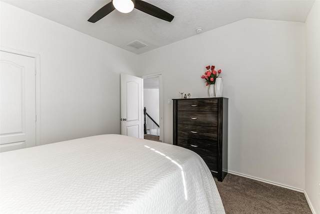 bedroom with ceiling fan, dark carpet, and lofted ceiling