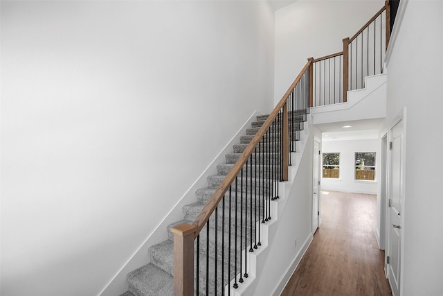 stairway with hardwood / wood-style floors and a high ceiling