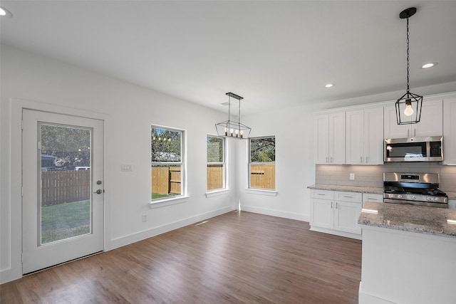745 20th St, Hempstead, TX 77445 - kitchen with white cabinets, hanging light fixtures, appliances with stainless steel finishes, and tasteful backsplash