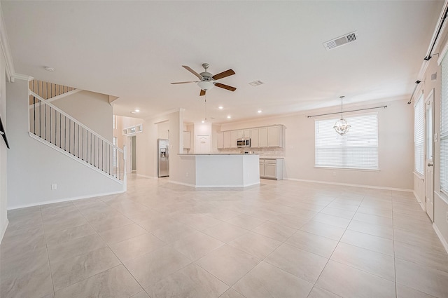 unfurnished living room featuring light tile patterned floors, ceiling fan with notable chandelier, and ornamental molding