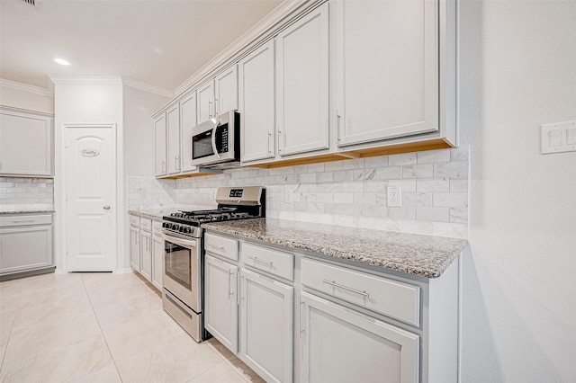 kitchen with light stone countertops, appliances with stainless steel finishes, decorative backsplash, light tile patterned floors, and ornamental molding