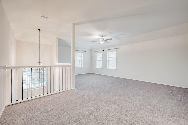 empty room with ceiling fan with notable chandelier and carpet floors