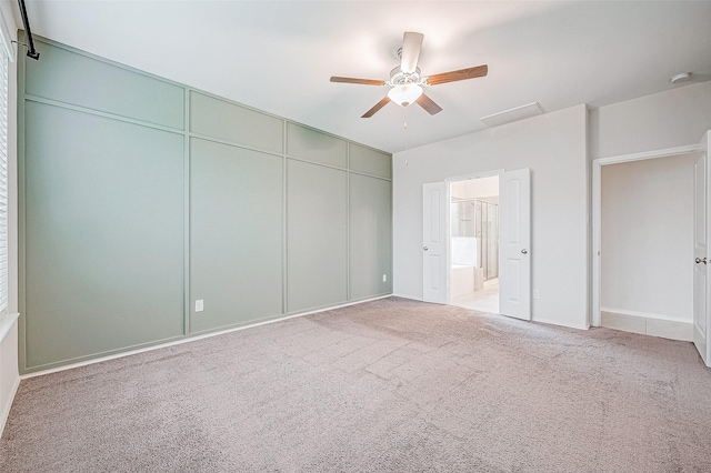 unfurnished bedroom featuring ceiling fan, light colored carpet, ensuite bathroom, and a closet