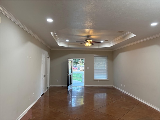 empty room featuring crown molding, ceiling fan, dark tile patterned floors, a textured ceiling, and a tray ceiling