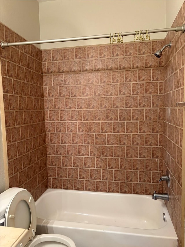 bathroom with tiled shower / bath combo and toilet