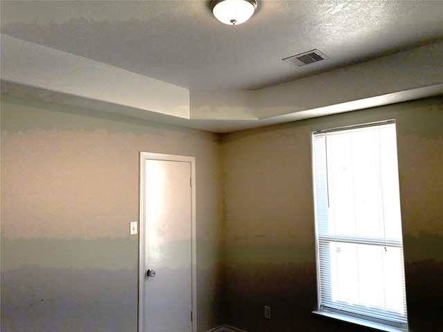 unfurnished room with a textured ceiling and a raised ceiling