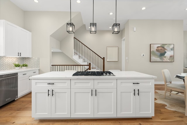 kitchen featuring white cabinets, hanging light fixtures, stainless steel dishwasher, light stone countertops, and gas cooktop