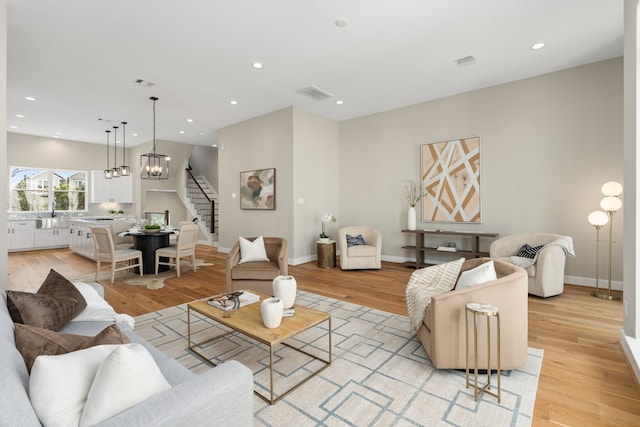 living room with light wood-type flooring, sink, and an inviting chandelier