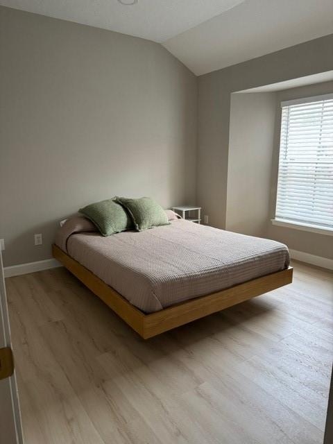 bedroom featuring vaulted ceiling and light wood-type flooring