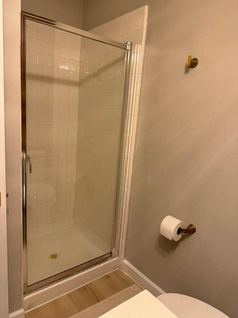 bathroom featuring hardwood / wood-style floors, toilet, and walk in shower