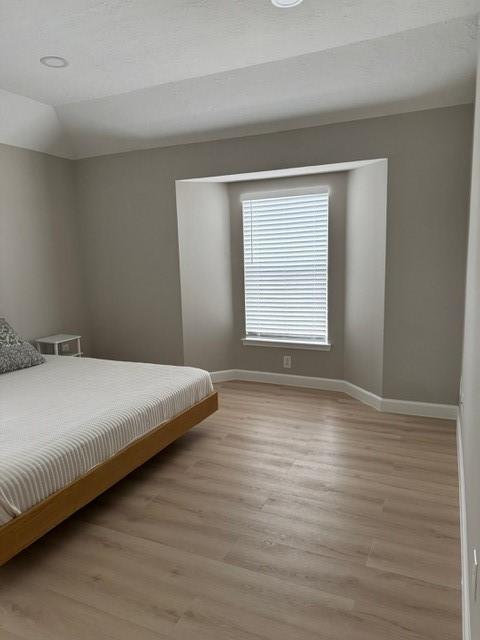 bedroom with lofted ceiling and light wood-type flooring